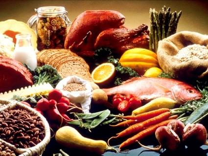 	A display of healthy foods on a table. Foods include beans, grains, cauliflour, cantelope, pasta, bread, orange, turkey, salmon, carrots, turnips, zucchini, snowpeas, string beans, radishes, asparagus, summer squash, lean beef, tomatoes, and potatoes.